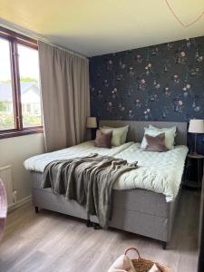 a bedroom with a large bed with floral wallpaper at Seaside Stay Haverdal in Haverdal