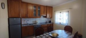 a kitchen with wooden cabinets and a table and a refrigerator at Casa Ramos in Mogadouro