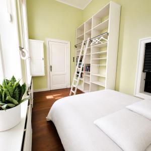 a bedroom with a white bed and a ladder at Spacious manor house with pool & playground in Essen