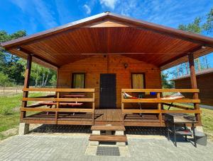 a wooden cabin with a roof and a porch at Domki Letniskowe Morena in Ostrowo