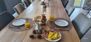a wooden table with a breakfast of eggs bacon and toast at Chambre d'hôte Escale piscine in Ghislenghien