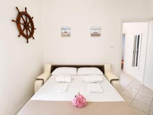 a white bed with two pillows and a flower on it at Appartamento Sole in Tessera
