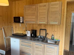 a kitchen with wooden cabinets and a sink and a refrigerator at Domki Letniskowe Morena in Ostrowo +18 photos