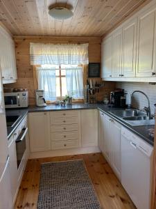 a kitchen with white cabinets and a sink at Lyngbu på Stavtjørn in Vikeså