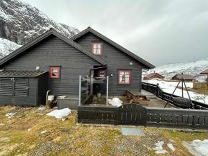 a black house with red windows and a snow covered mountain at Lyngbu på Stavtjørn in Vikeså +6 photos