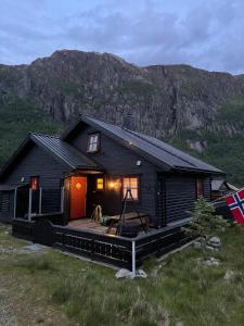 a black house with a deck with a mountain in the background at Lyngbu på Stavtjørn in Vikeså