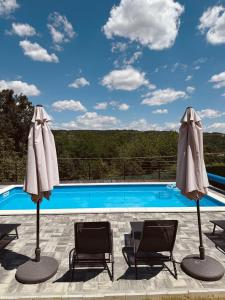a pool with two chairs and two umbrellas at Villa Jaram Private Pool & BBQ Escape in Jarmenovci