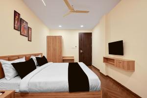 a bedroom with a bed and a tv on the wall at Hotel O Grand Shivay in Indore
