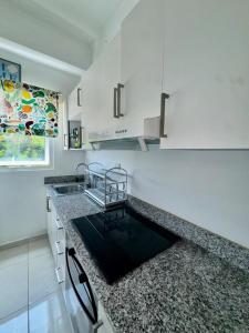 a kitchen with white cabinets and a black counter top at Tepuy Residential in Juan Dolio +5 photos