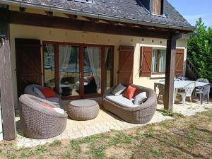 a patio with two wicker chairs and a table at Charmante maison avec jacuzzi privatif in Saint-Salvadour