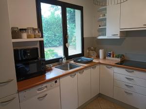 a kitchen with a sink and a microwave and a window at Charmante maison avec jacuzzi privatif in Saint-Salvadour