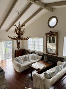 a living room with couches and a table and a mirror at Bycroft Lodge in Karaka