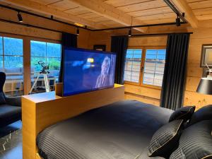a bedroom with a large flat screen tv on top of a bed at Tatra Whisper Chalet in Ząb