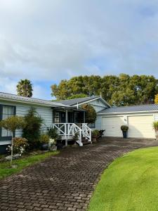 a white house with a porch and a driveway at Bycroft Lodge in Karaka