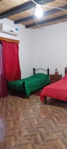 a room with two beds with green sheets in it at Hospedaje Ayla in Tinogasta