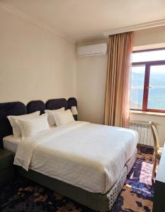 a bedroom with a large bed with a large window at Kefilyan Family Hotel in Haghpat