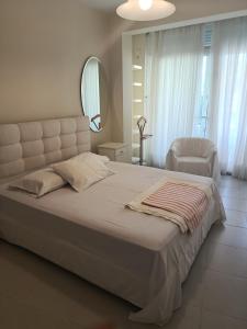 a bedroom with a large white bed and a mirror at Evi's house in Iraklitsa