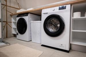 two washing machines and a dryer in a laundry room at Mahne Apartment in Kranj
