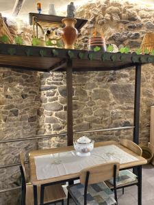 a table and chairs in front of a stone wall at El renacer de Flor - Casa turística in Chandreja