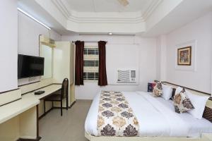 a bedroom with a bed and a desk and a television at Hotel O Midtown in Raipur