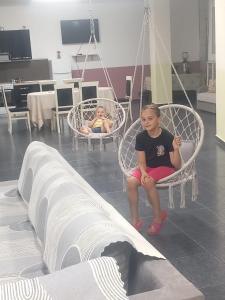 two children sitting in swinging chairs in a room at House Leon in Krujë