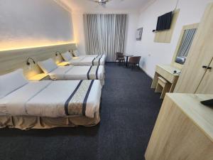 a hotel room with three beds and a table at Rahat Alubur Hotel in Medina