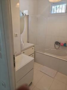 a white bathroom with a tub and a sink and a mirror at Evi's house in Iraklitsa