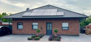 a red brick house with solar panels on the roof at Barrierefreie Ferienwohnung Abendrot in Pewsum, 1 - 4 Personen in Krummhörn