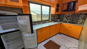 a kitchen with orange cabinets and an empty refrigerator at Afridi Apartment in Murree