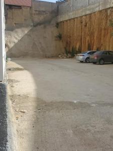 a parking lot with two cars parked next to a wall at Appartement a bir mourad rais in Birmandreis