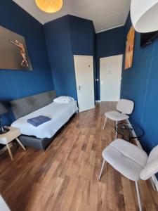a bedroom with blue walls and a bed and two chairs at Pension Delfzijl in Delfzijl