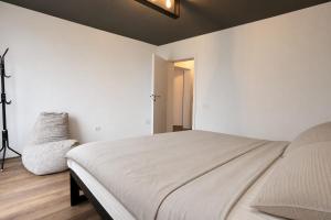 a white bedroom with a bed and a chair at Black Villa in Prizren