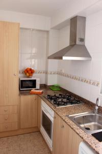 a kitchen with a sink and a stove top oven at Apartamentos Guillem in Playa de Miramar