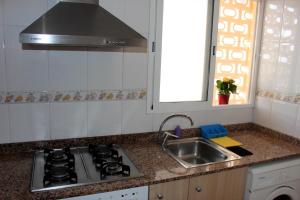 a kitchen with a stove and a sink and a window at Apartamentos Guillem in Playa de Miramar