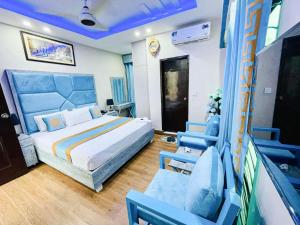 a bedroom with a bed and two blue chairs at Hotel Johar View in Lahore