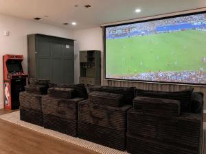 a room with couches and a large screen with a soccer game at 1 Block to Beach 150" Theater PS5 Arcade in Seaside Heights +26 photos