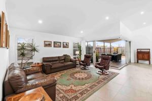 a living room with a leather couch and chairs at Tomakin Tonic in Tomakin