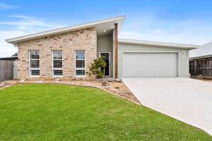 a house with a garage and a grass yard at Tomakin Tonic in Tomakin +7 photos