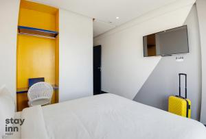 a bedroom with a bed and a tv and a chair at Hotel STAY INN in Agadir