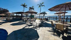 a patio with chairs and tables and umbrellas on the beach at Flat 337 vista lago no Lake side in Brasília