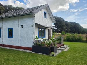 a small white house with plants in a yard at Domek wakacyjny Domysłów in Domysłów