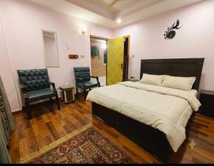 a bedroom with a large bed and two chairs at AZH Hotel & Rooms in Islamabad