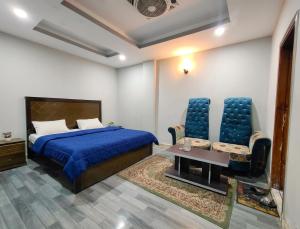 a bedroom with a bed and two chairs and a table at AZH Hotel & Rooms in Islamabad