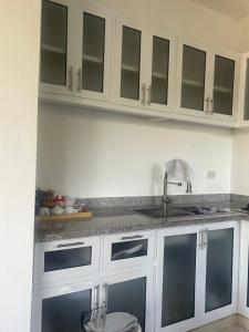 a kitchen with white cabinets and a sink at GG residencial in El Factor
