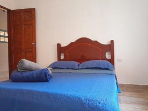 a bedroom with a blue bed with a wooden headboard at Recanto do Gigante Adormecido in Joanópolis