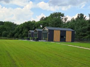 a couple of black buildings in a field at Domki nad Grabią in Rokitnica