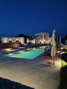 a swimming pool with chairs and umbrellas at night at Masseria Camerlengo in Castellana Grotte