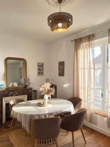 a dining room with a table with chairs and a mirror at La pause Saumuroise in Saumur