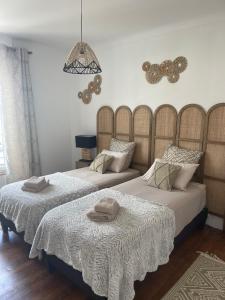 a bedroom with two beds with white sheets and a chandelier at La pause Saumuroise in Saumur