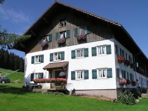 ein großes weißes Gebäude mit Blumen an den Fenstern in der Unterkunft Lindenhof in Sulzberg
